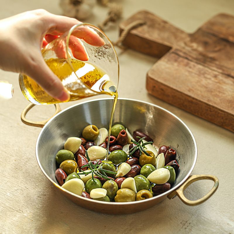 오븐 팬에 그린올리브와 블랙올리브, 마늘, 로즈마리를 넣은 후 올리브오일을 넣어주세요. 크러쉬드 레드페퍼와 후춧가루를 뿌려주세요.