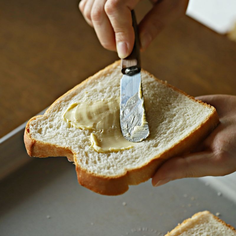 식빵 한쪽 면에 버터를 바른 후 오븐 팬에 얹어주세요. 숟가락으로 가장자리 1cm 정도 남기고 꾹꾹 눌러주세요.