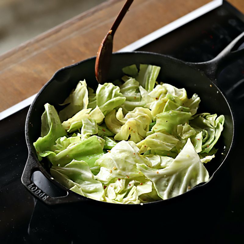 달궈진 팬에 기름을 두르고 다진 마늘을 넣어 향을 낸 후 양배추를 넣어 중불에서 볶아주세요.
