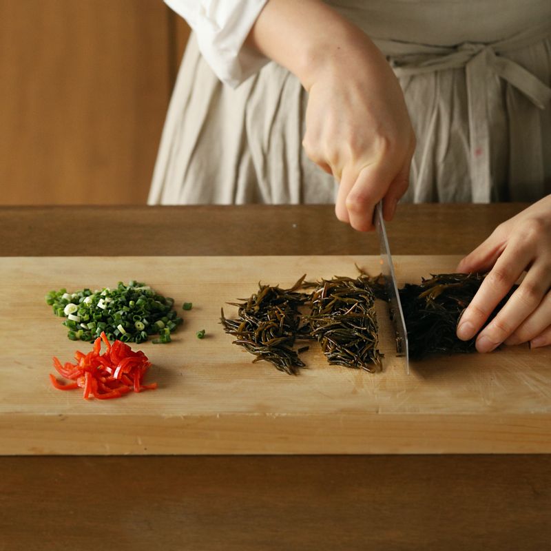 데친 톳은 3~4cm 정도의 길이로 자르고 홍고추는 씨를 뺀 후 2cm 길이로 얇게 채를 썰어주세요. 쪽파는 송송 썰어주세요.